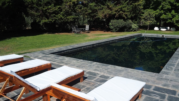 A swimming pool with lounge chairs and a stone deck. - Villa Victoria Lodge (Maipu)