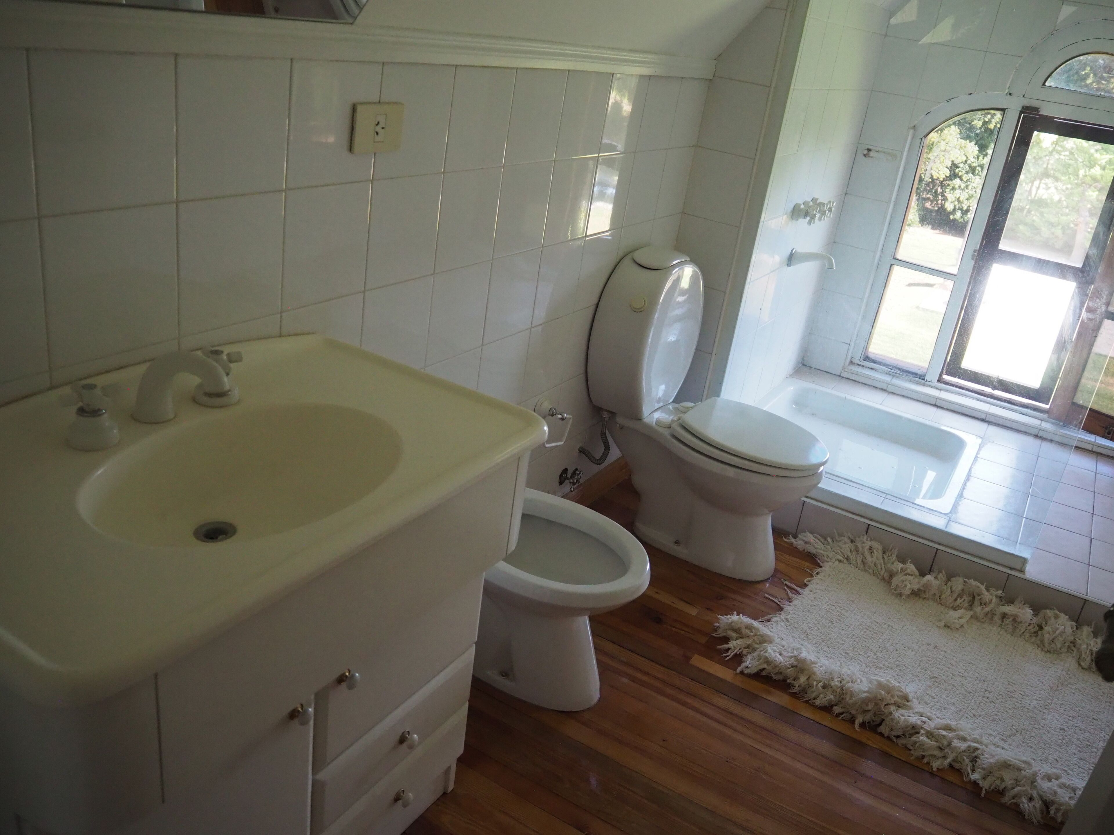 Un baño con lavamanos, inodoro y ventana.