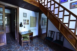 Traditional room with a wooden staircase, desk, and framed artwork.