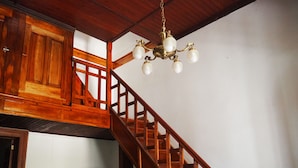 A wooden staircase with a chandelier, wooden paneling, and two framed pictures on the wall. - Villa Victoria Lodge (Maipu)