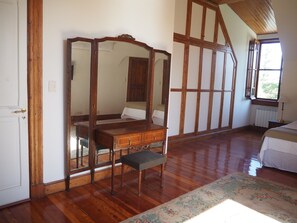 Traditional bedroom with a high ceiling, ornate bed frame, and polished wood floor.