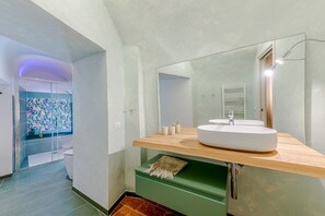 Une salle de bain moderne avec un grand miroir, un lavabo rond et un espace douche.