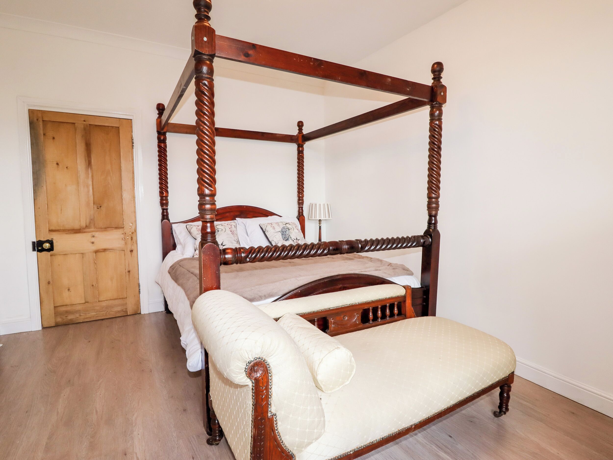 A four-poster canopy bed with a matching footboard and a cushioned bench.