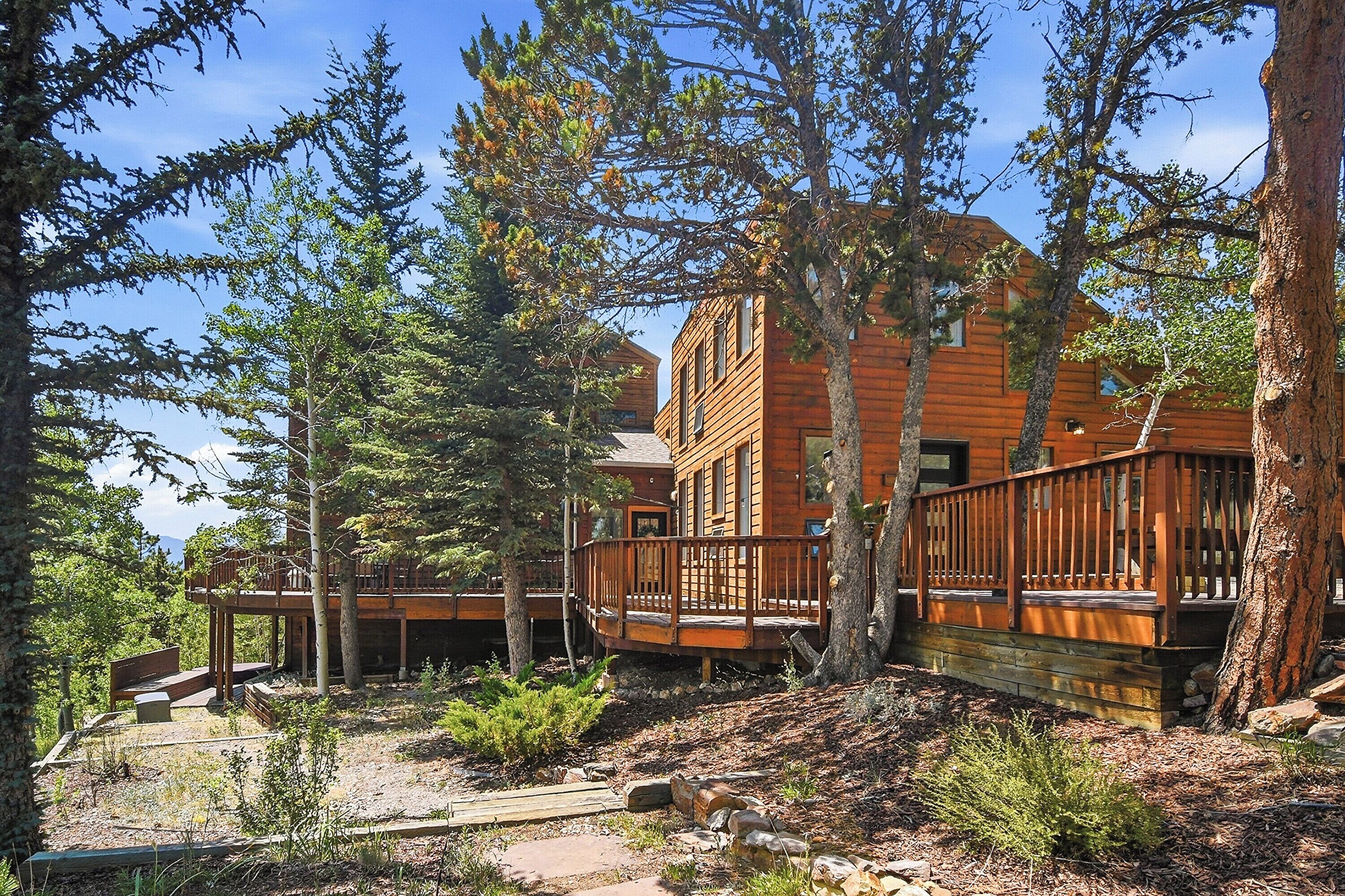 Une cabane dotée d’une terrasse, entourée d’arbres.