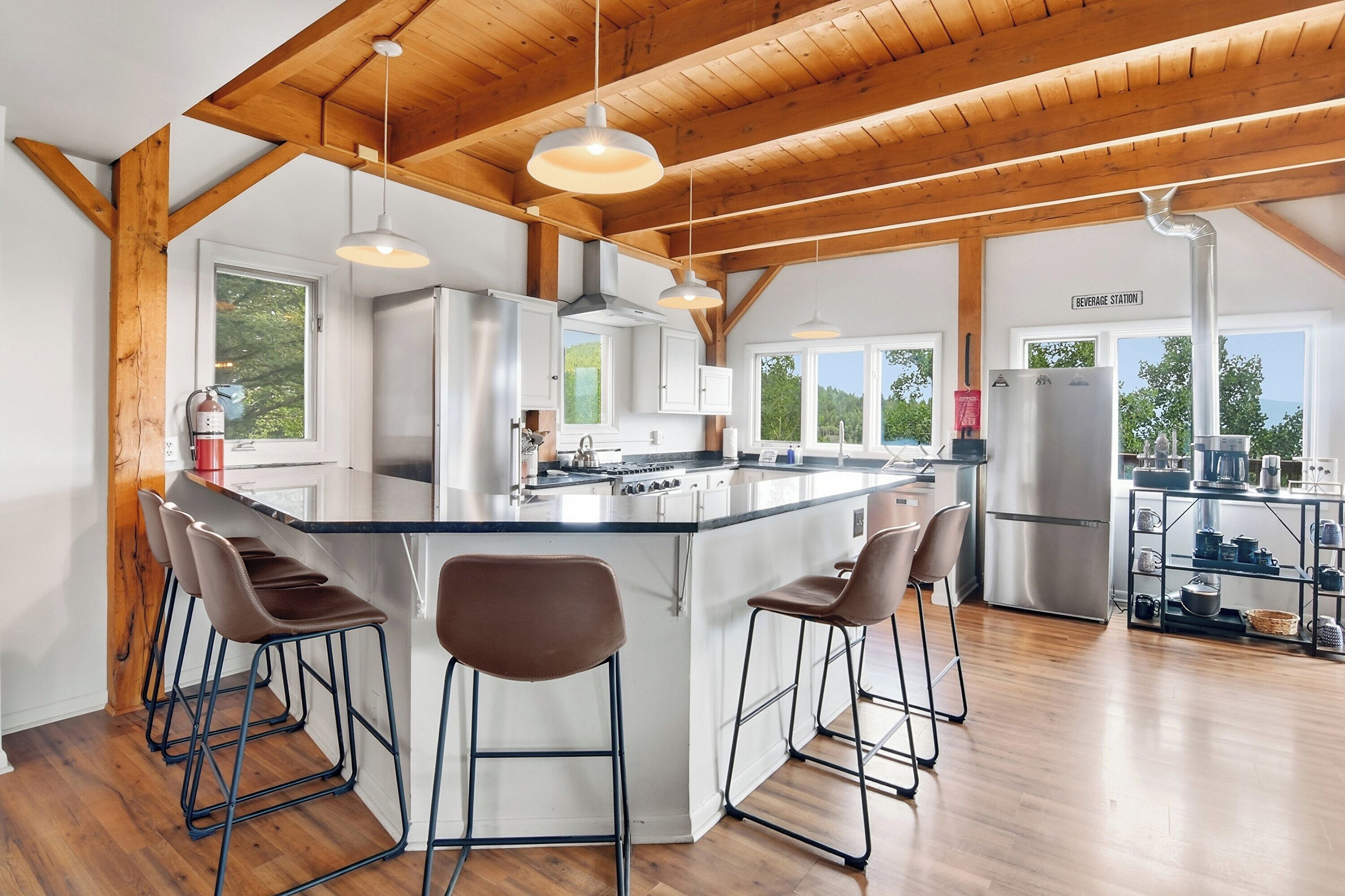 A modern kitchen with a central island, bar stools, and a beverage station.