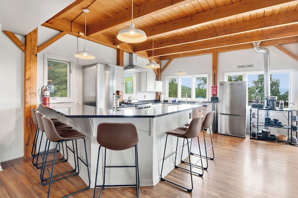 A modern kitchen with a central island, bar stools, and a beverage station.