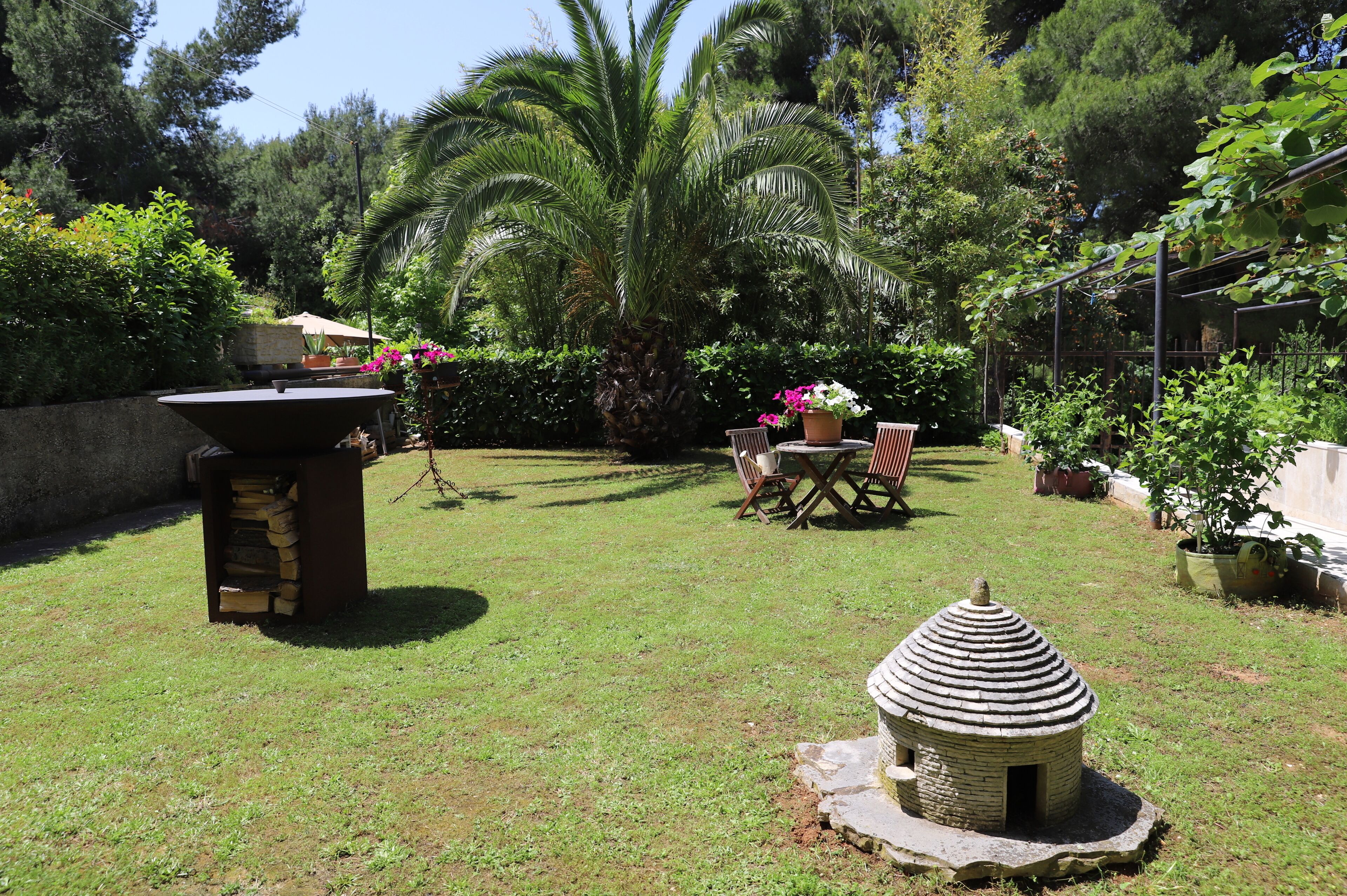 A backyard with a stone barbecue, a small brick structure, and a dining area with chairs and a table.