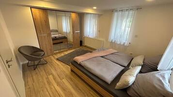 A bedroom with a bed, a chair, and a wardrobe with a mirror.