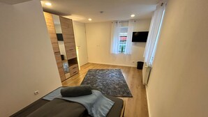 A bedroom with a bed, a wooden wardrobe, a TV mounted on the wall, and a window with curtains. - Modern vacation apartment in Altertheim near kist Würzburg highway A3 A81 (Altertheim)