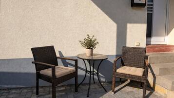 Deux fauteuils en osier avec des coussins, une petite table ronde et une plante en pot.