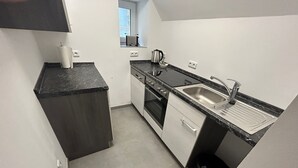 A compact kitchen with a stove, oven, sink, and a small window. - Modern vacation apartment in Altertheim near kist Würzburg highway A3 A81 (Altertheim)