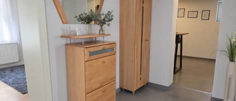 A room with a wooden dresser, a mirror, and a vase with flowers.