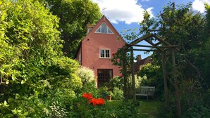 A red house surrounded by lush greenery and a wooden pergola. - The Tallow Factory - Historic Tudor Home in Dedham (Dedham)