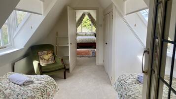 A room with two beds, a chair, and a window.