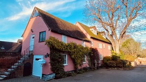 A pink house with a sloped roof, a staircase, and a tree in front. - The Tallow Factory - Historic Tudor Home in Dedham (Dedham)