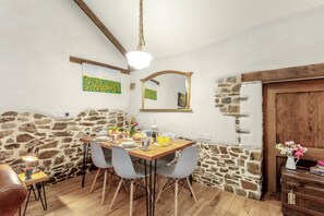 A dining area with a stone wall, wooden ceiling beams, a hanging light fixture, and a wooden door. - 2 Bed in Torrington (oc-p27344) (Langtree)