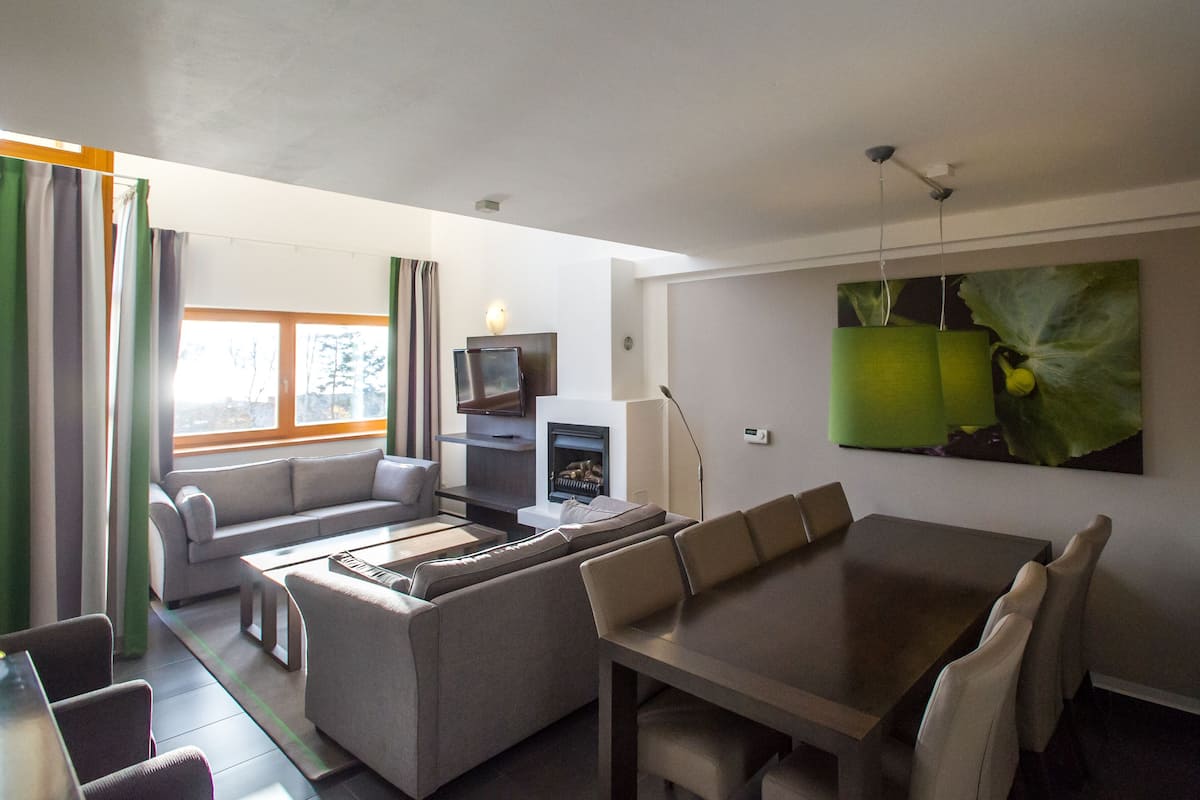 Una sala de estar moderna con un sofá, una mesa de comedor y un televisor de pantalla plana.