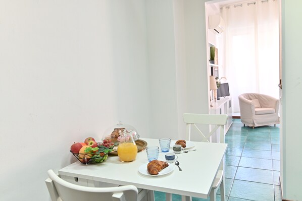 A breakfast table with fruits, a glass of orange juice, and a croissant. - IzzHome Holiday Terrace (Cagliari)