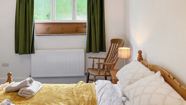 A hotel room with a bed, a chair, a lamp, and a window with curtains. - Coldwell Street Cottage (Wirksworth)