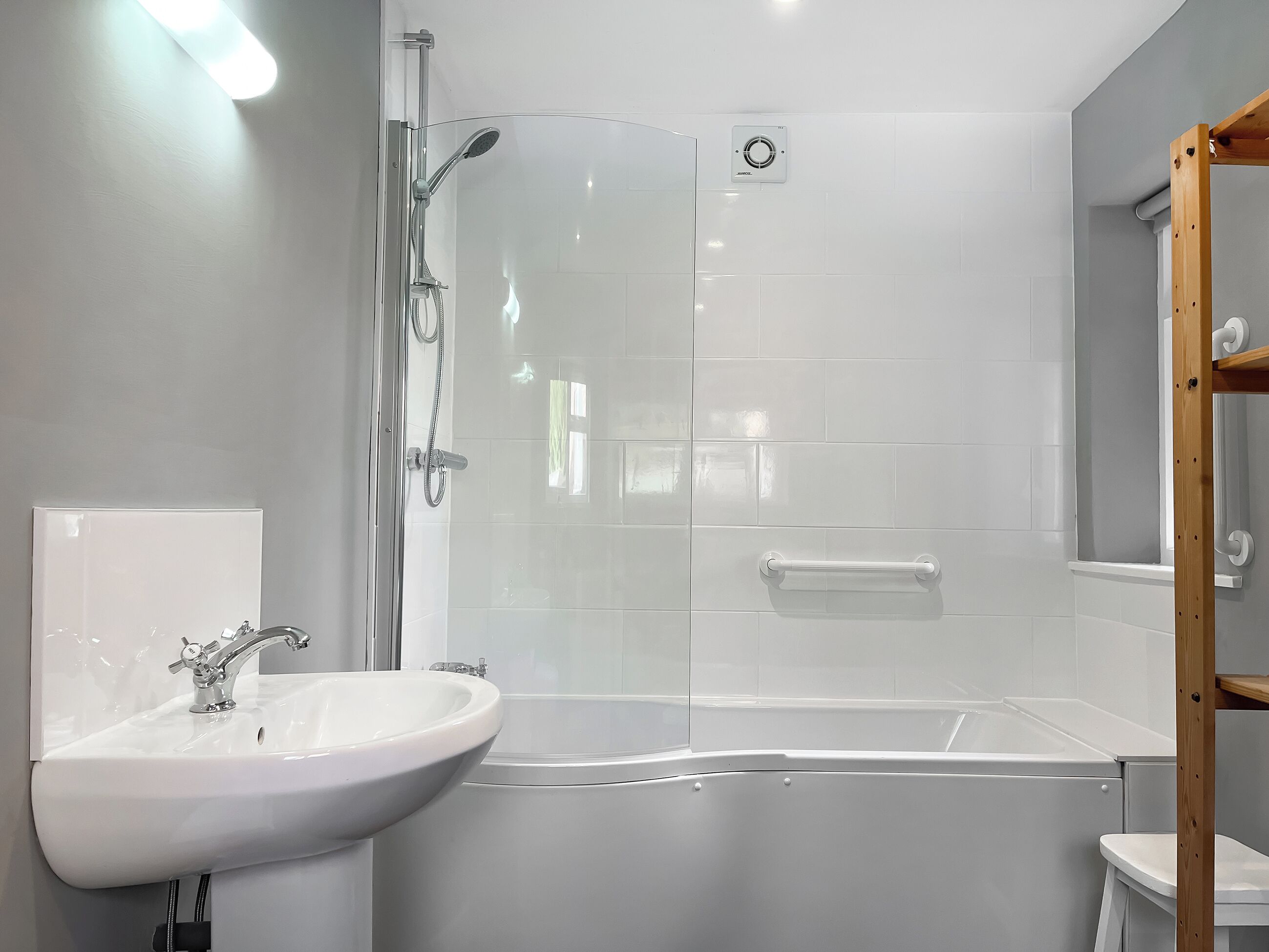 A modern bathroom with a glass-enclosed shower, a white sink, and a bathtub.