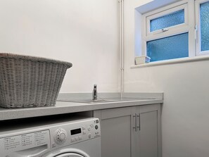 A compact laundry area with a washing machine, a drying rack, and a window with a view.