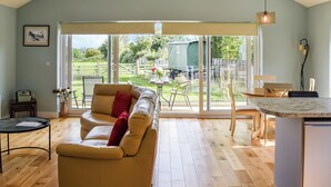 A spacious living area with a sofa, a dining table, and a kitchen island. - An ideal destination for relaxation, comfort and immersion in nature’s beauty. (Old Buckenham)