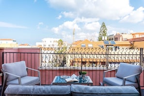 A balcony with two chairs, a table, and a book. - KEDEM - By Beach Apartments TLV (Tel Aviv)