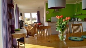A dining area with a wooden table, chairs, and a vase of tulips.