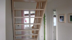 A wooden staircase with a handrail, a small rug at the bottom, and a door leading to another room.
