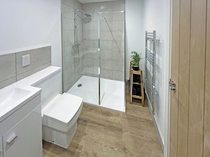A modern bathroom with a shower, toilet, and sink.