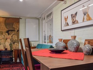 A dining area with a wooden table, chairs, and a red placemat. There are decorative vases on the table and a framed picture of dogs on the wall. - 3 bedroom accommodation in Chalkhouse Green, near Reading (Chalkhouse Green, near Reading)