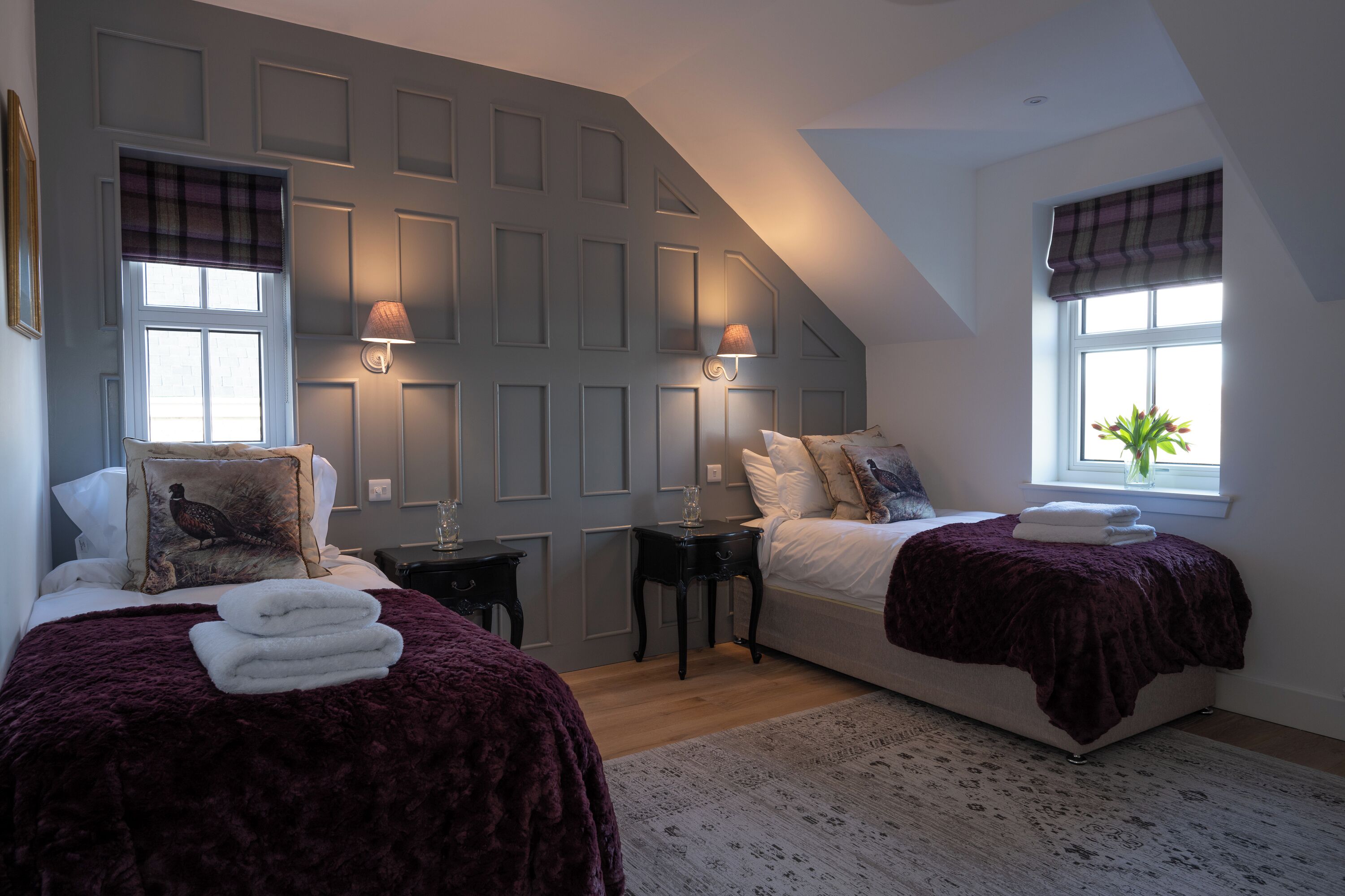 A bedroom with two beds, a window with a view, and a wall with a geometric pattern.