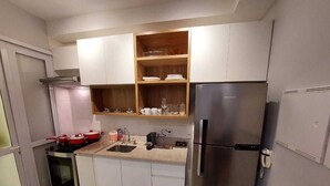 A compact kitchen with white cabinets, a stainless steel refrigerator, a built-in oven, and a countertop with a sink. - Swimming pool apartment. High standard for family or business people! 4 minutes from the subway! (Pinheiros São Paulo)