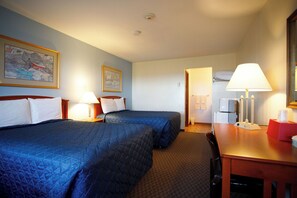 A hotel room with two beds, a desk, a chair, a lamp, a TV, and a painting on the wall.