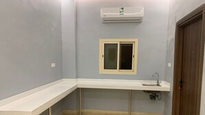 A small, modern bathroom with a white countertop, a sink, and an air conditioning unit above. - Aya Hostel For Shared Bedrooms (Madinah)