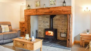 A cozy living room with a stone fireplace, a wooden mantel, and a sofa. - The Stables - UK45090 (Longdyke, near Morpeth)