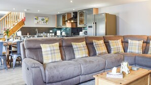 A modern living room with a grey sectional sofa, wooden coffee table, and a kitchen in the background. - The Stables - UK45090 (Longdyke, near Morpeth)