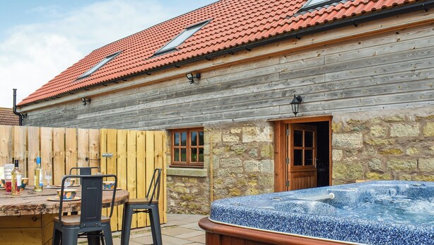 A wooden house with a stone wall, a wooden door, and a hot tub. - The Stables - UK45090 (Longdyke, near Morpeth)