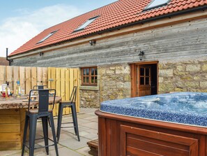 Ein Holzhaus mit Mauerwerk, einer Holztür und einem Whirlpool.