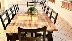 A wooden dining table with six chairs, a potted plant, and a view of the ocean. - Incredible 6 bed 5 bath detached villa in the exclusive area of Puerto Calero. (Puerto Calero)