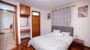 Een slaapkamer met een groot bed, een houten garderobe en een spiegel.