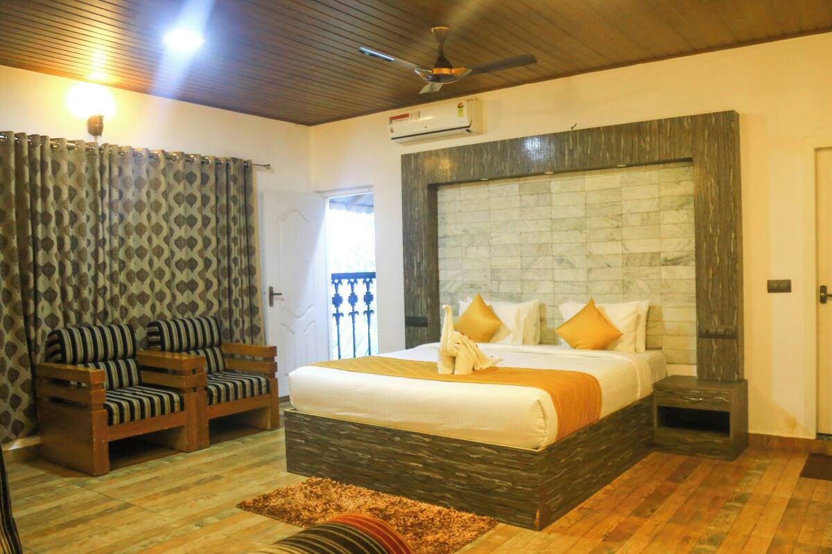 A bedroom with a large bed, a wooden headboard, a ceiling fan, and a window with curtains.