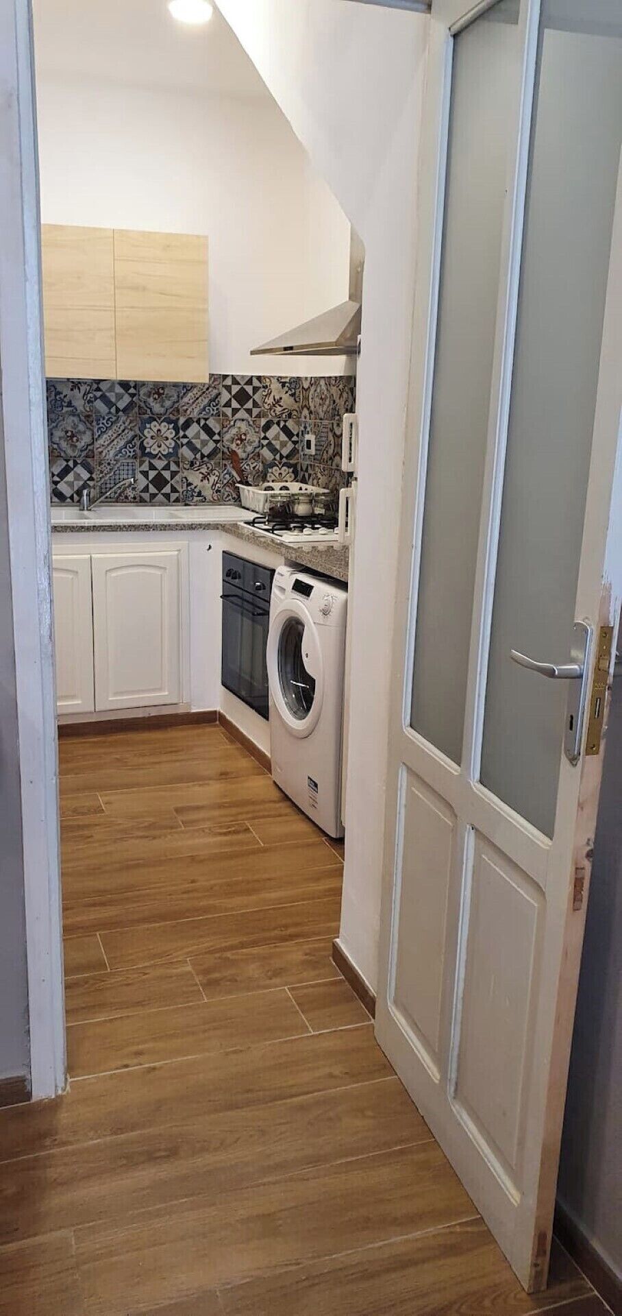 Une cuisine équipée d’un lave-linge, d’une cuisinière et d’un plan de travail carrelé.