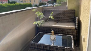 Varanda com móveis de vime, uma mesa de vidro e um lustre.