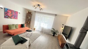 Uma sala de estar moderna com sofá, cama, televisão e lareira.