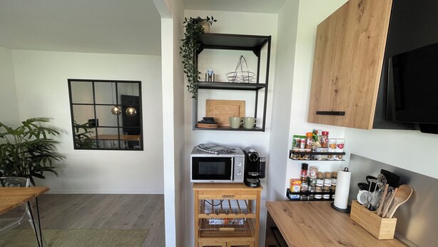 Uma cozinha compacta com micro-ondas, cafeteira e armários de madeira.