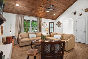 Relax in this inviting living room with a high ceiling, sofa, coffee table, and armchair.