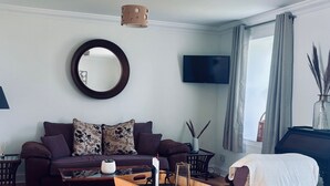 A living room with a sofa, coffee table, TV, and a window with curtains. - Bracken Cottage - sleeps 4 guests  in 2 bedrooms (Argyll)
