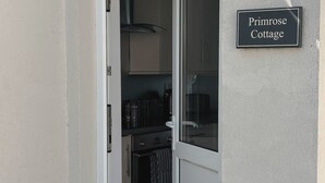 Ovi johtaa keittiöön, ja sen yläpuolella on kyltti, jossa lukee: ”Primrose Cottage”.