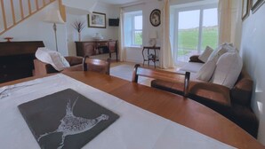 Ein geräumiges Wohnzimmer mit einer Holztreppe, einem Essbereich und großen Fenstern mit Blick ins Freie.